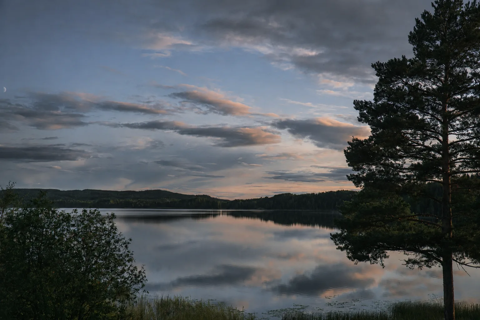 Lago sereno ao crepúsculo, com a margem em sombra